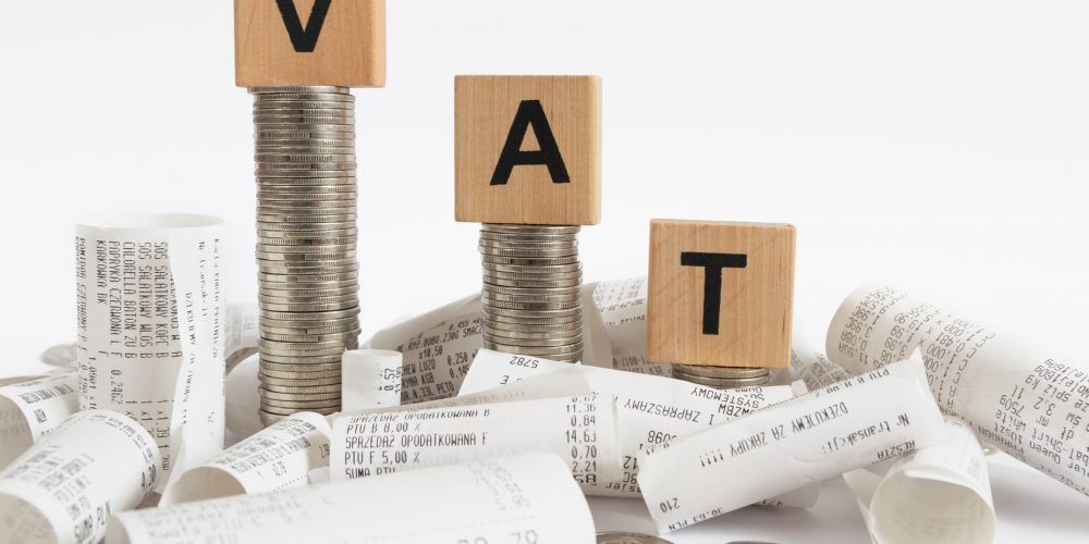 Rows of coin stacks with toy blocks among the receipts  symbolizing value added tax