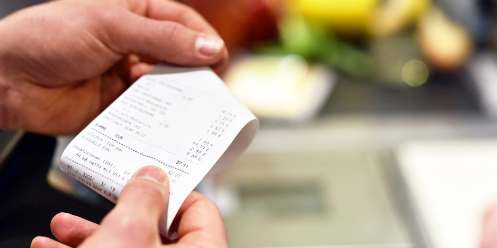 Hände mit Kassenzettel an der Kasse im Supermarkt // hands with receipt at the checkout in the supermarket